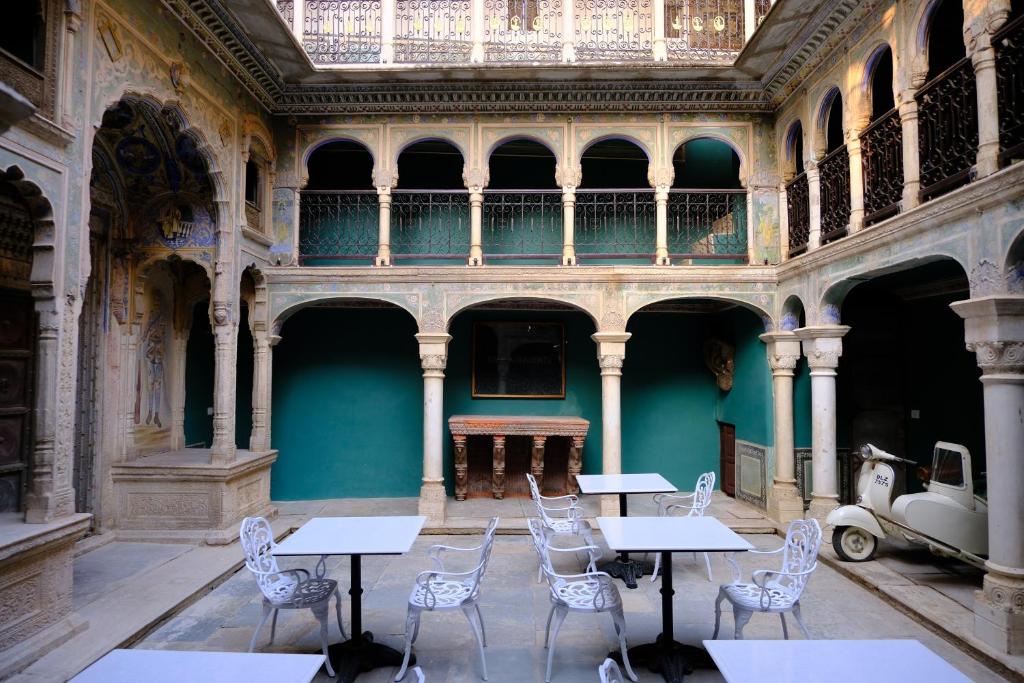 una habitación vacía con mesas y sillas en un edificio en Vivaana Museum Hotel, en Nawalgarh