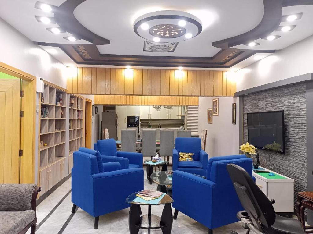 een woonkamer met blauwe stoelen en een tv bij White Lotus Karachi in Karachi