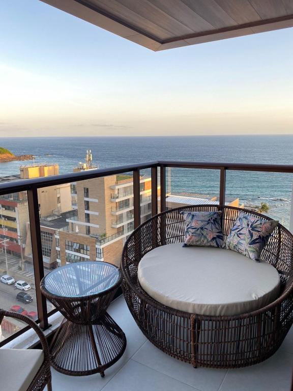 a balcony with a chair and a table and the ocean at Studio 1quarto Vista Mar Barra Business & Travel in Salvador