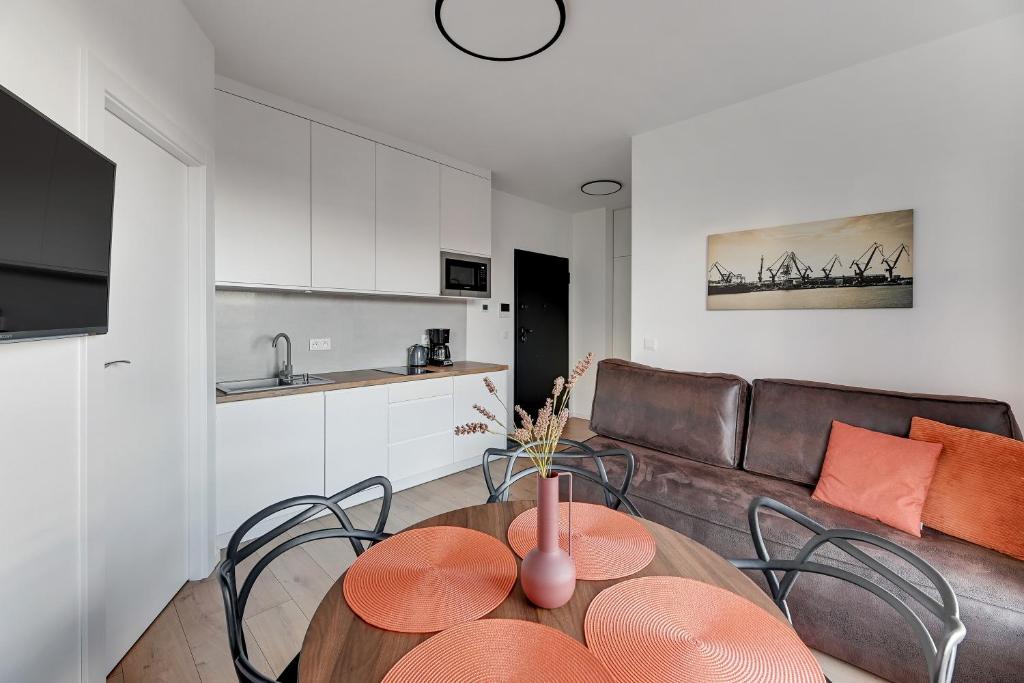 a living room with a table and chairs and a couch at DOKI Living & Foodhall Apartament in Gdańsk