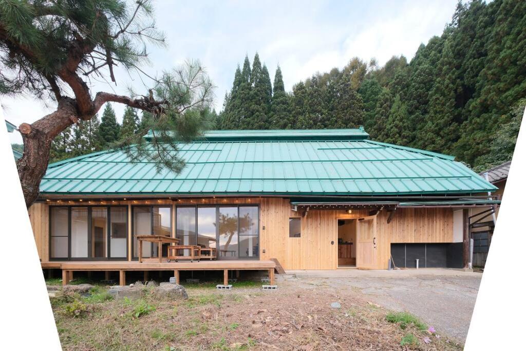 uma casa com um telhado verde e uma mesa em プラベート薪サウナ付 1日1組限定ease1高山村 em Takayama