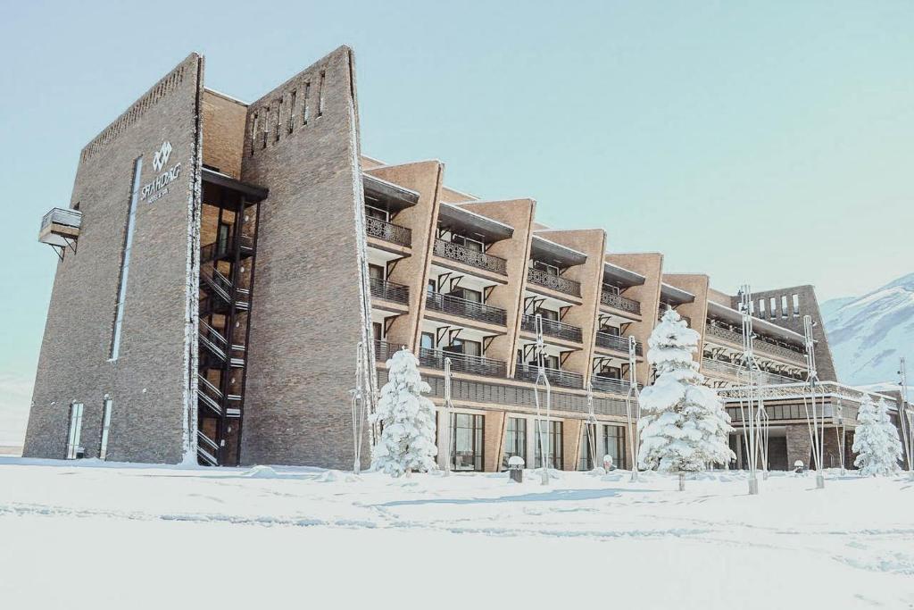 a large building in the snow with snow covered trees at Shahdag Hotel & Spa in Shahdag