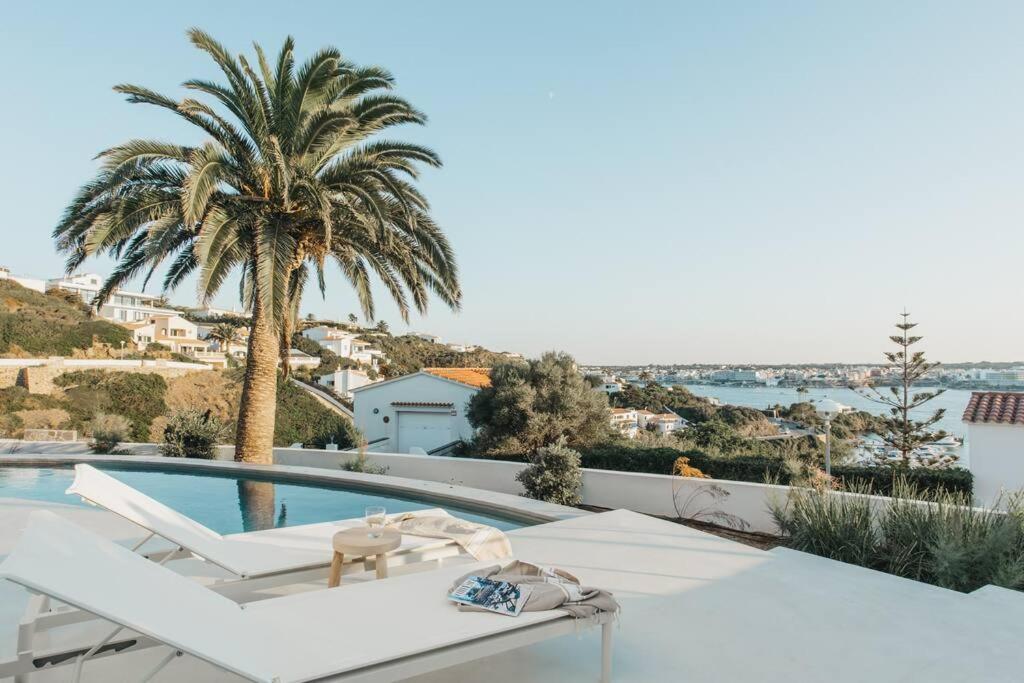a villa with a pool and a palm tree at Villa Alma luxe & sea views in Cala Llonga
