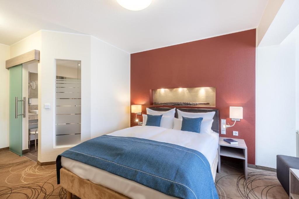 a bedroom with a large bed with a blue blanket at Hotel Elisenhof Mönchengladbach in Mönchengladbach