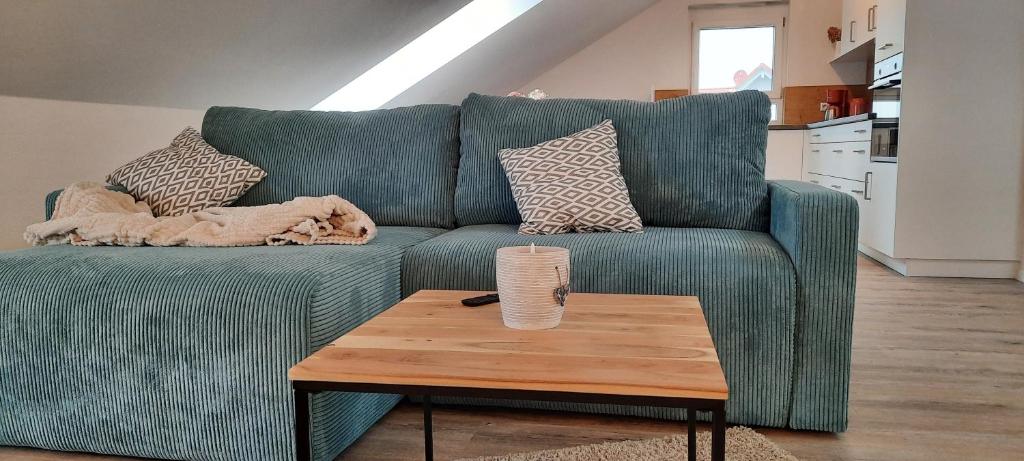 ジンツハイムにあるNeubau Ferienwohnung Kleine Auszeitの緑のソファ(枕付)、木製のコーヒーテーブルが備わります。