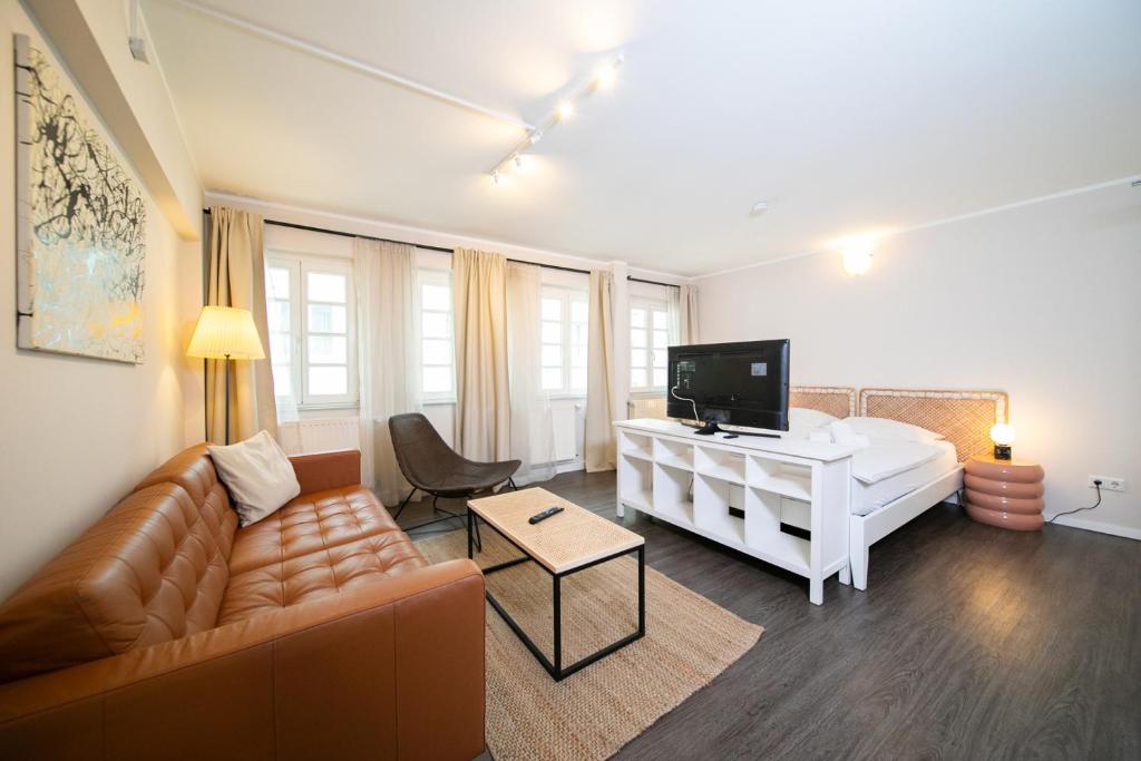 a living room with a bed and a couch and a television at Favorite Stays -Suite and More - Altstadt in Düsseldorf