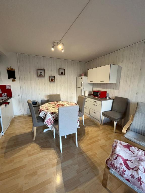 ein Wohnzimmer mit einem Tisch und Stühlen sowie eine Küche in der Unterkunft T3 La Grande Chaume Le Sauze in Enchastrayes