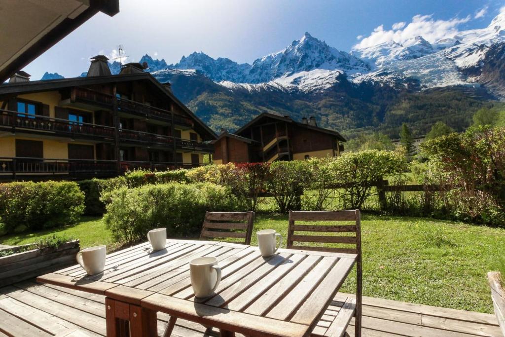 une table en bois avec des chaises et des montagnes en arrière-plan dans l'établissement Les Gaillands, à Chamonix-Mont-Blanc