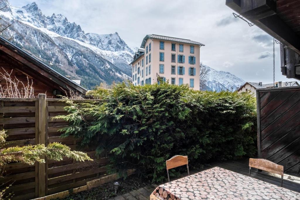 un bâtiment avec deux chaises devant une haie avec des montagnes dans l'établissement Chalet Vorgeats 2 - 6 pers - Au pied de la Flégère - Golf - UTMB, à Chamonix-Mont-Blanc