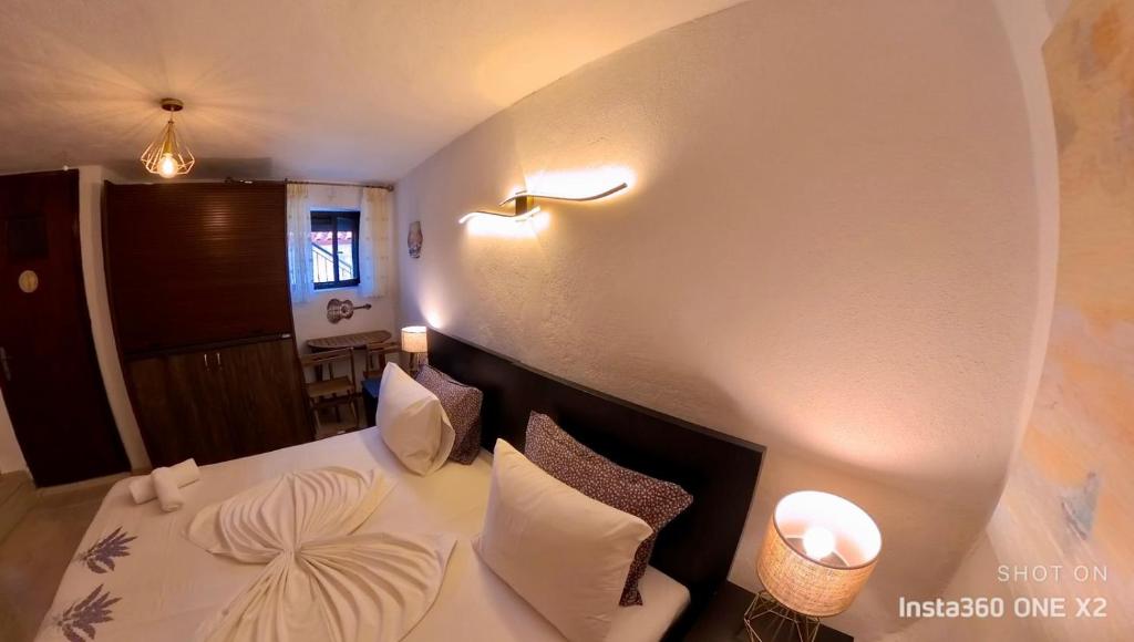 Schlafzimmer mit einem Bett mit weißer Bettwäsche und Kissen in der Unterkunft Sun Oniro Studio in Samothráki