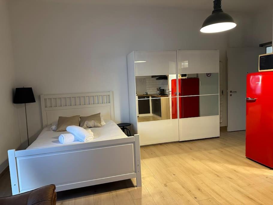a bedroom with a white bed and a red refrigerator at Studio très pratique ! in Le Mont-sur-Lausanne