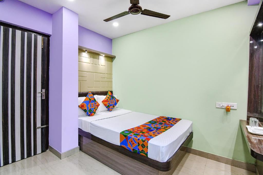 um quarto com uma cama com uma parede roxa em FabExpress Laxmi Inn em kolkata