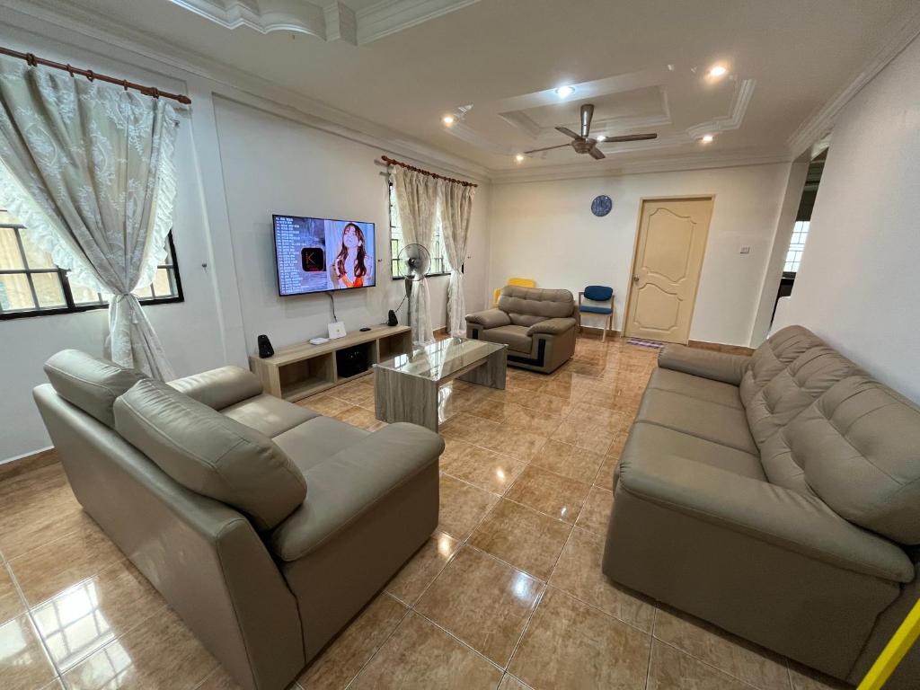 a living room with two couches and a flat screen tv at [El Casa] Homestay Miri (8 Pax) in Miri