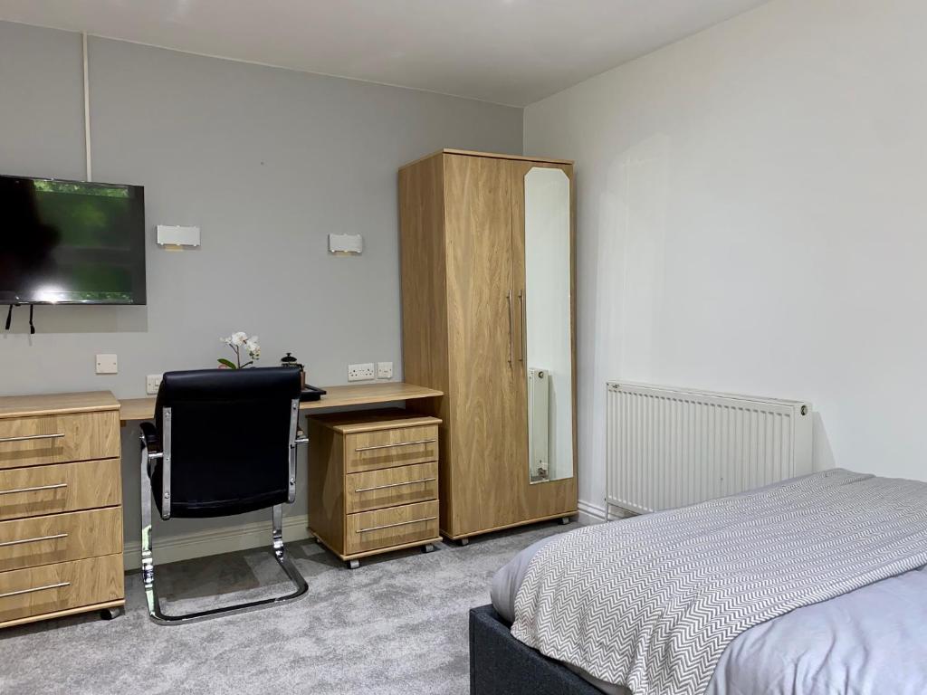 Dormitorio con cama, escritorio y TV en Sapphire Suites, en Reading