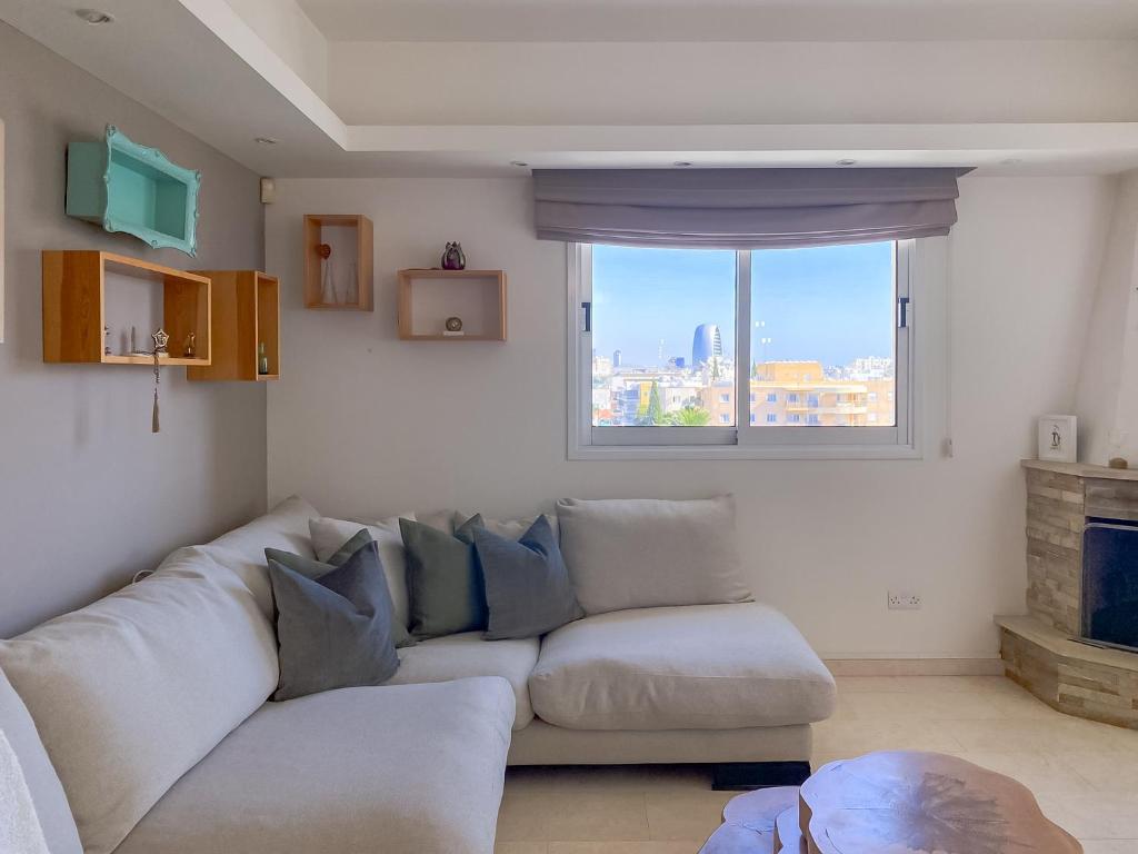 een woonkamer met een bank en een raam bij Phaedrus Living: Erato Seaview Luxury Penthouse in Limassol