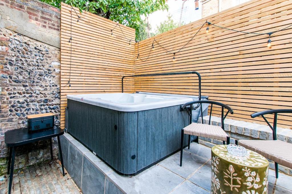 a hot tub sitting on a patio next to a wooden wall at Coastal Gem With Hot Tub in Kent
