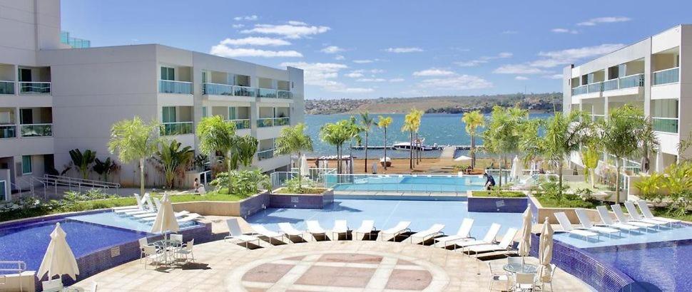 a large swimming pool with chairs and a building at Luxuoso Flat Brisas do Lago Terraço Aconchegante in Brasilia