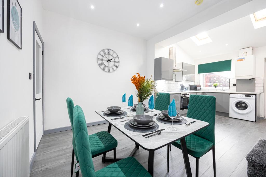comedor y cocina con mesa y sillas verdes en Stunning Bolton Abode - Cinema Experience - Parking en Bolton