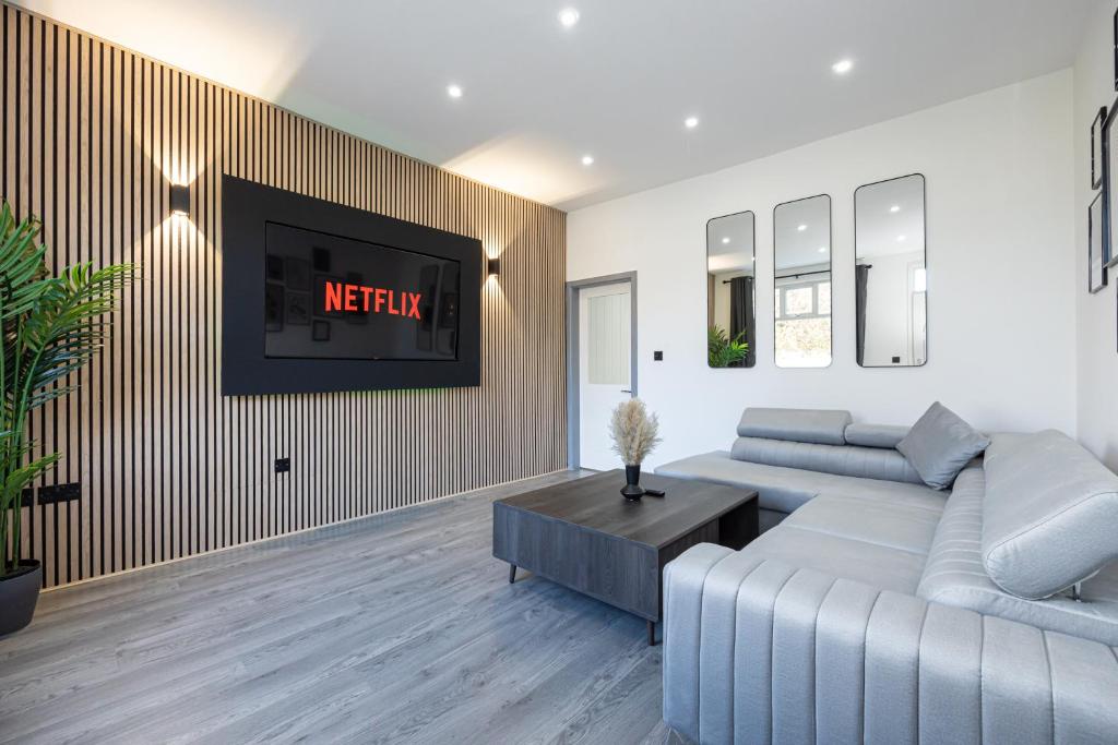 een woonkamer met een bank en een tv aan de muur bij Stunning Bolton Abode - Cinema Experience - Parking in Bolton