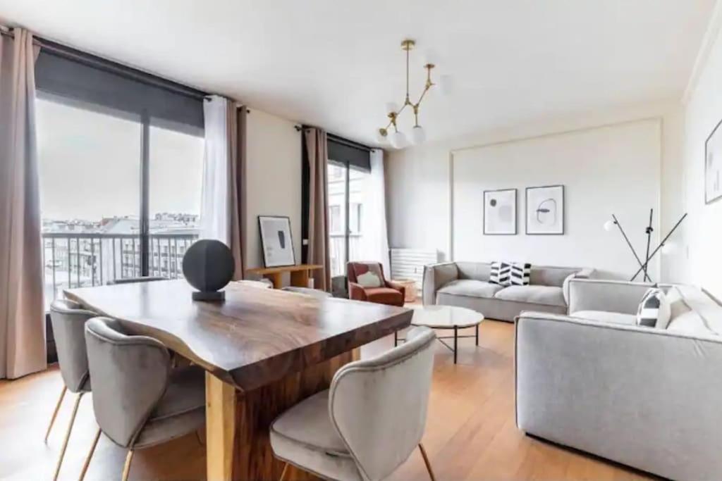uma sala de estar com um sofá, uma mesa e cadeiras em Avenue Montaigne : Luxury Apartment 4P/2BR em Paris