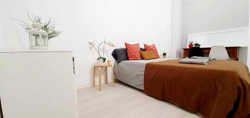 1 dormitorio con 1 cama con almohadas de color rojo y naranja en Hostal Urban Basic, en Hospitalet de Llobregat