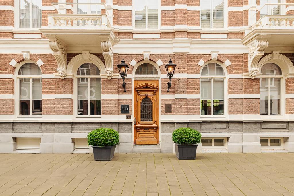 a building with a wooden door and two plants at Maison ELLE Amsterdam in Amsterdam