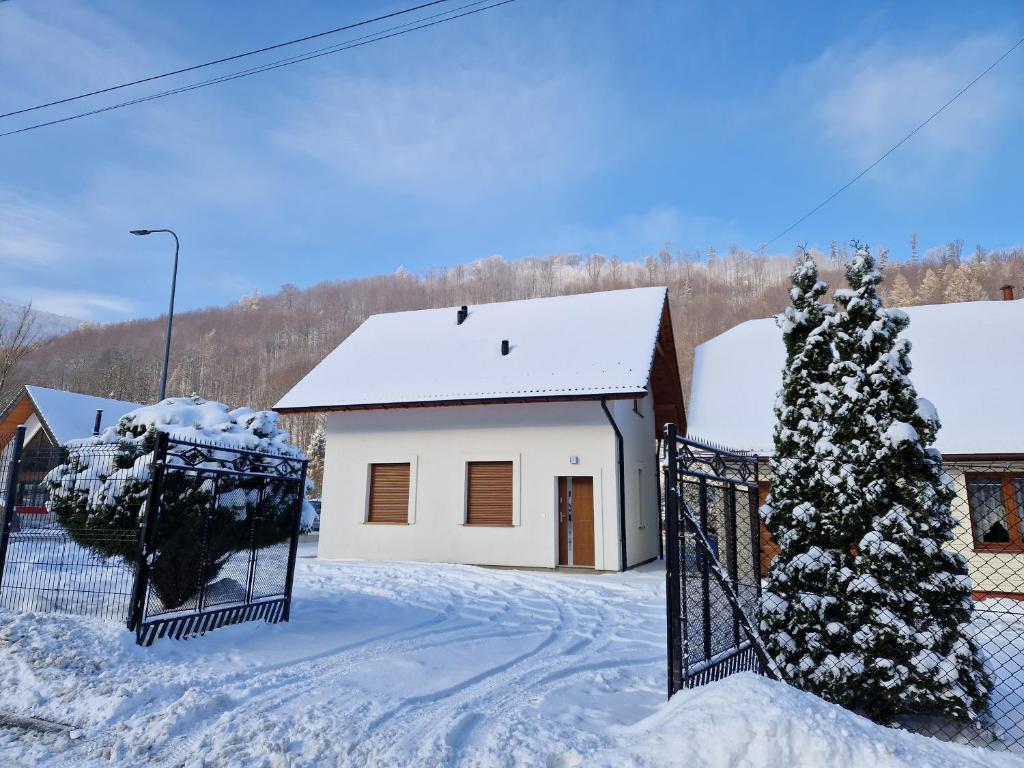 een huis met een hek in de sneeuw bij Domek Pod Klimczokiem in Bystra