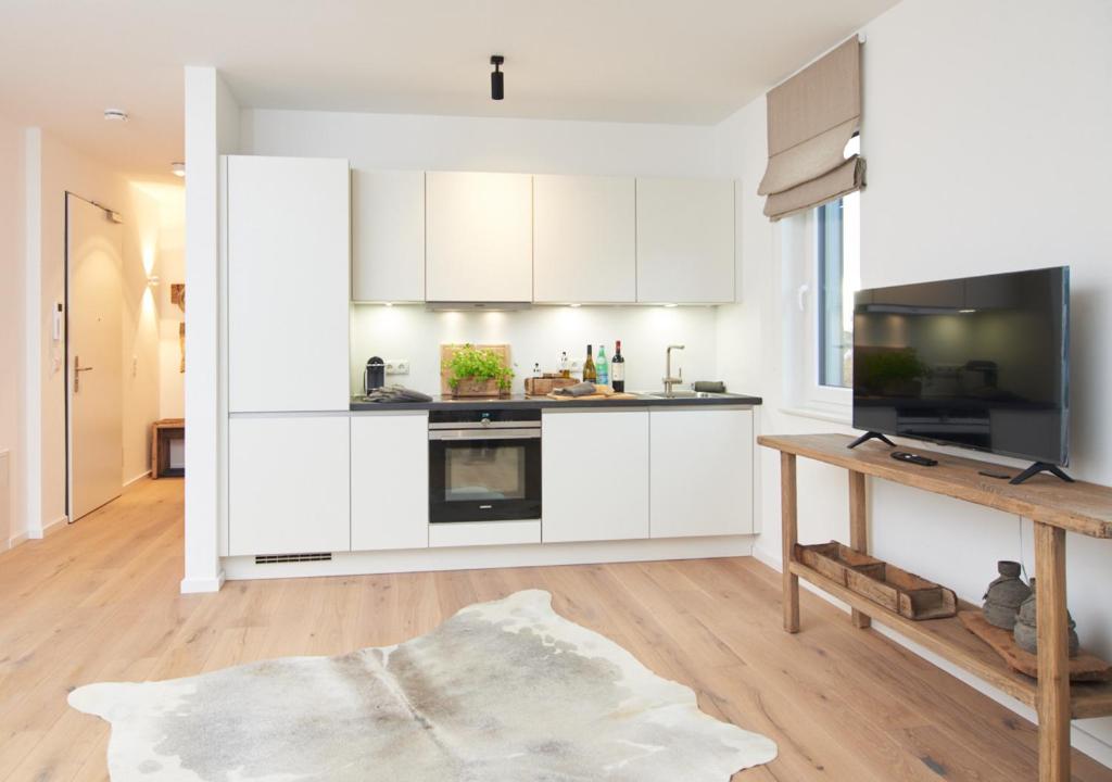 uma cozinha com armários brancos e uma mesa de madeira em Sunshine Suite - mit Meerblick em Timmendorfer Strand