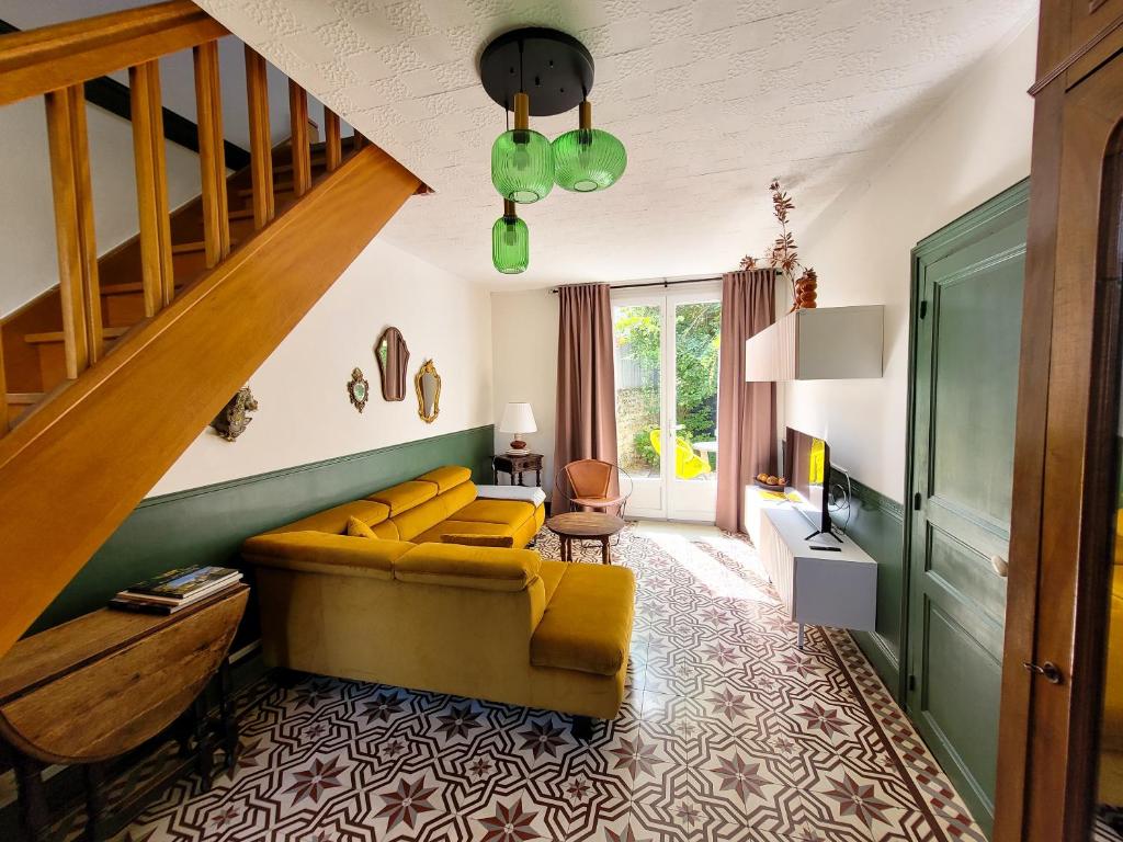 a living room with a yellow couch and a staircase at Guest House "Près des Montgolfières" in Angé