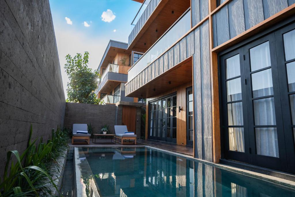 a house with a swimming pool next to a building at Secana Beachtown Resort & Residences in Canggu