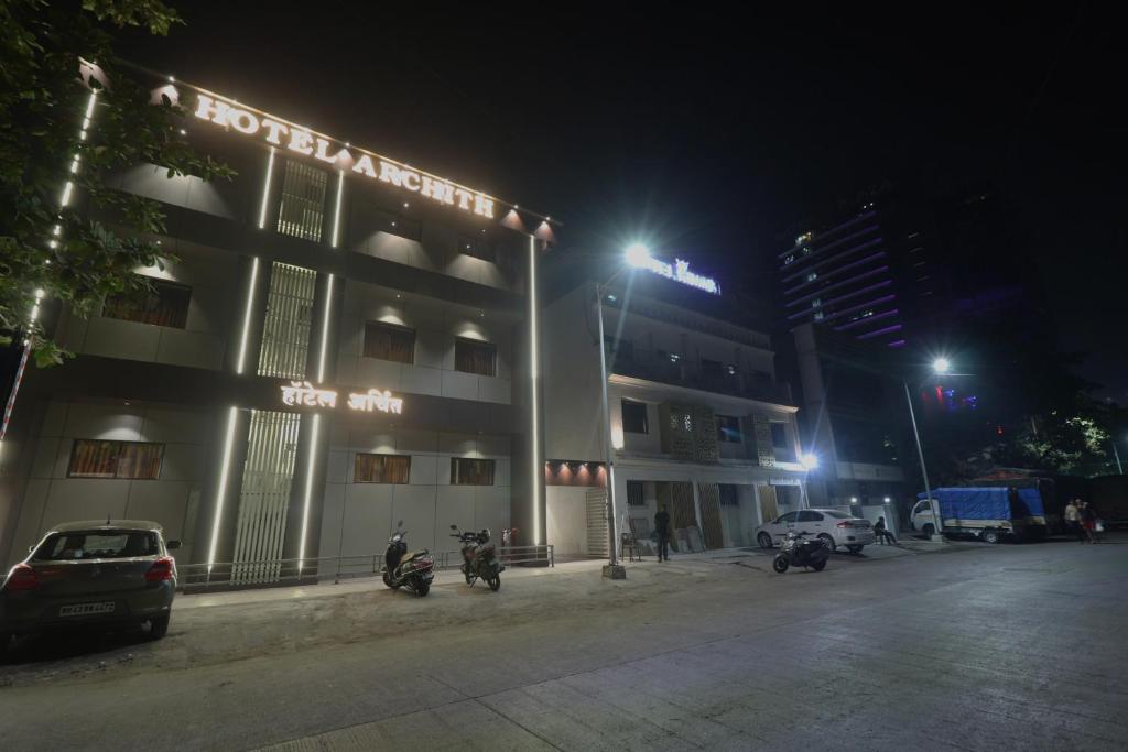 een gebouw waar 's nachts motoren voor geparkeerd staan bij Hotel Archith in Navi Mumbai