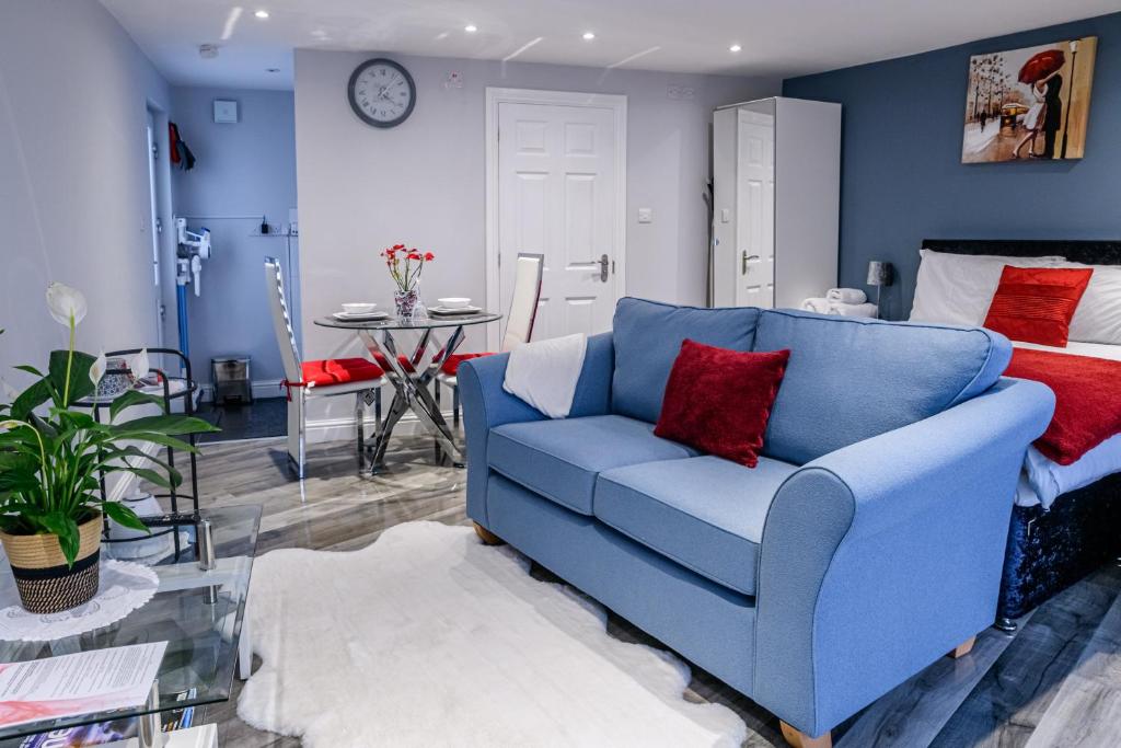 a blue couch in a living room with a bed at Luxury one bedroom guesthouse M6, Junction 10 Walsall in Willenhall