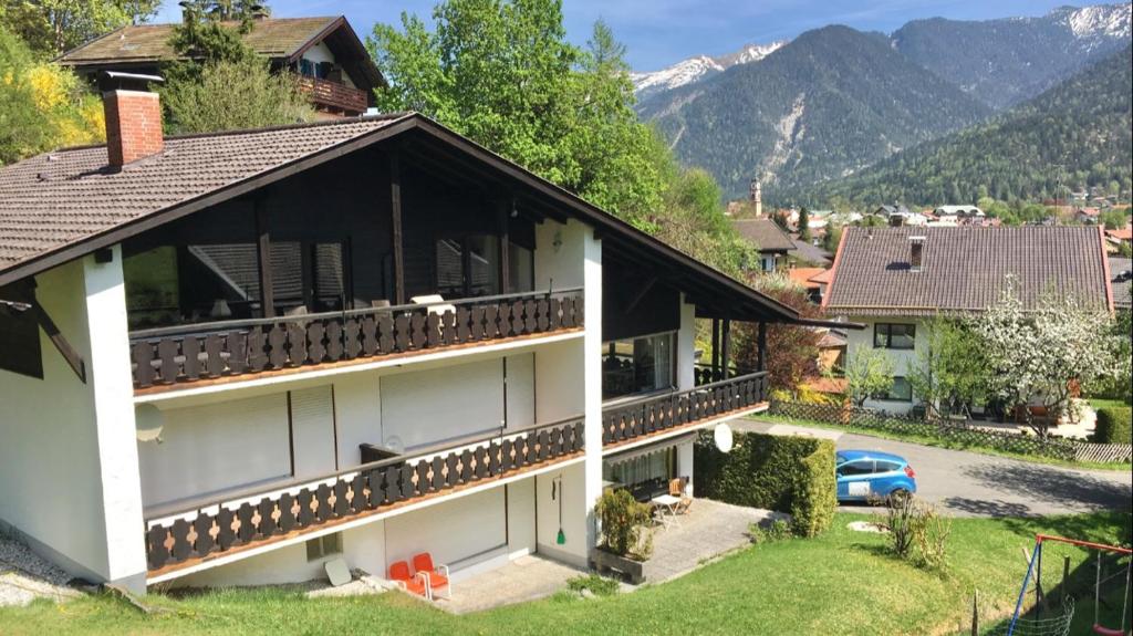 Casa con balcón con montañas en el fondo en Fewo Karwendelglühen, en Mittenwald
