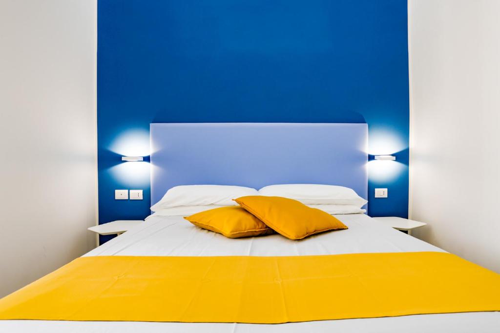 a bed with two yellow pillows and a blue wall at V10 GUESTHOUSE - Vanvitelli 10 in Naples