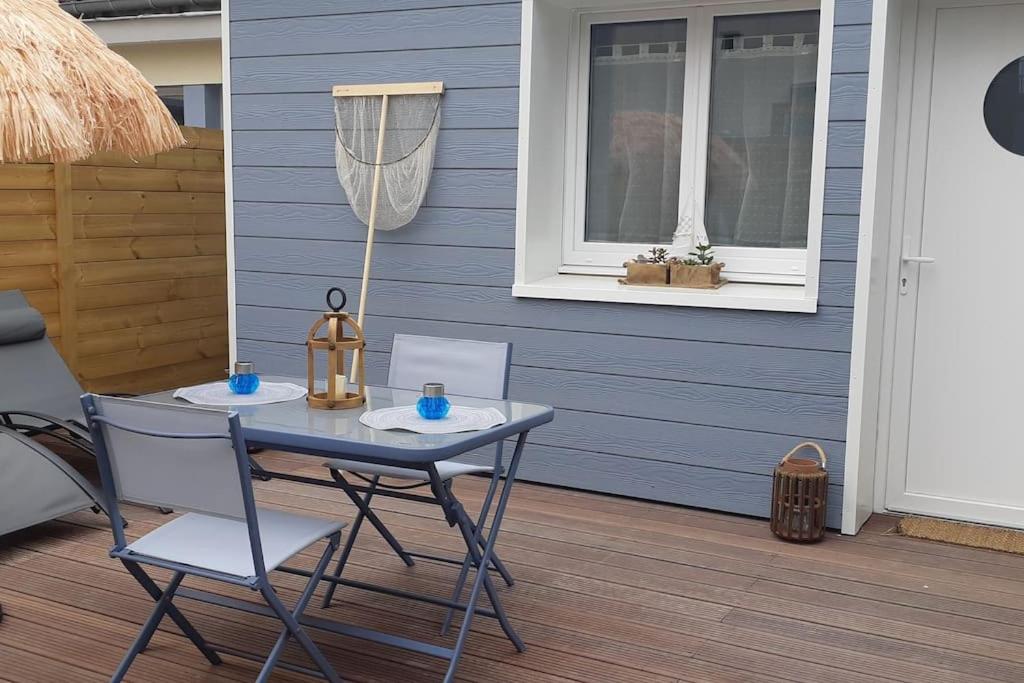 ein blaues Haus mit einem Tisch und Stühlen auf einer Veranda in der Unterkunft "La Mer Bohème", patio, parking privé, 8 mn plage in Le Portel
