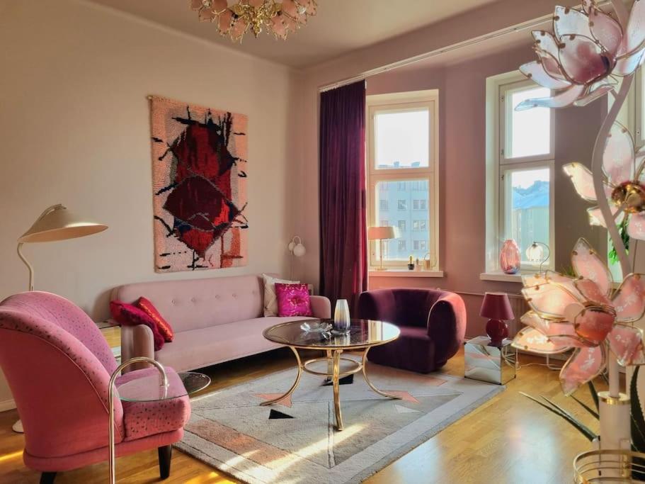 a living room with pink chairs and a couch at Lovely Vintage Suite in Helsinki