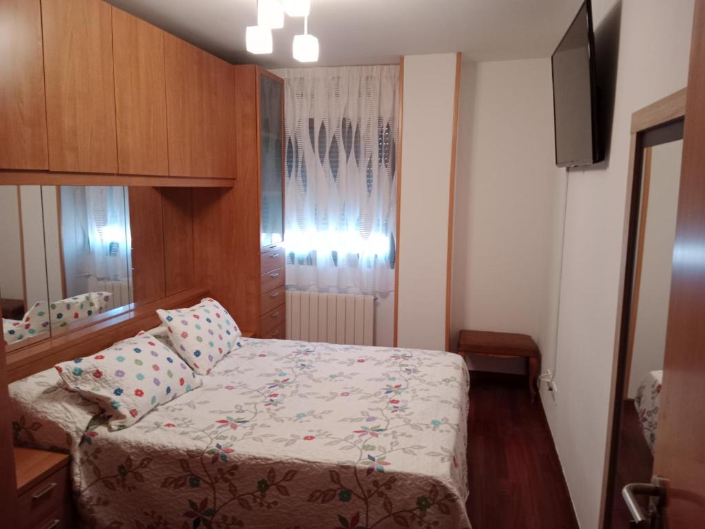 Un dormitorio pequeño con una cama y una ventana. en La casita de Miguel, con garaje y piscina, en Zamora