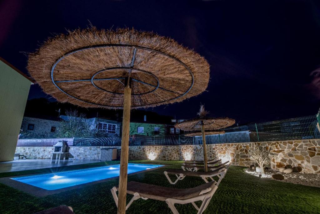 sombrilla y 2 sillas junto a la piscina por la noche en Casa El Rincón de Alberto con Calefacción y piscina, en Camelle