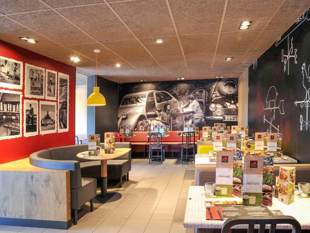 um restaurante com mesas e uma parede com uma imagem em Ibis Lyon Villefranche Sur Saone em Limas