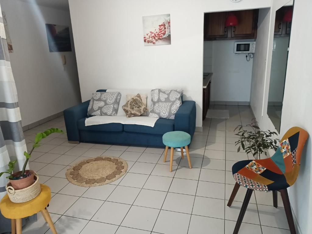 een woonkamer met een blauwe bank en stoelen bij blue and yellow, appartement au calme, avec piscine, WIFI in Saint-Denis