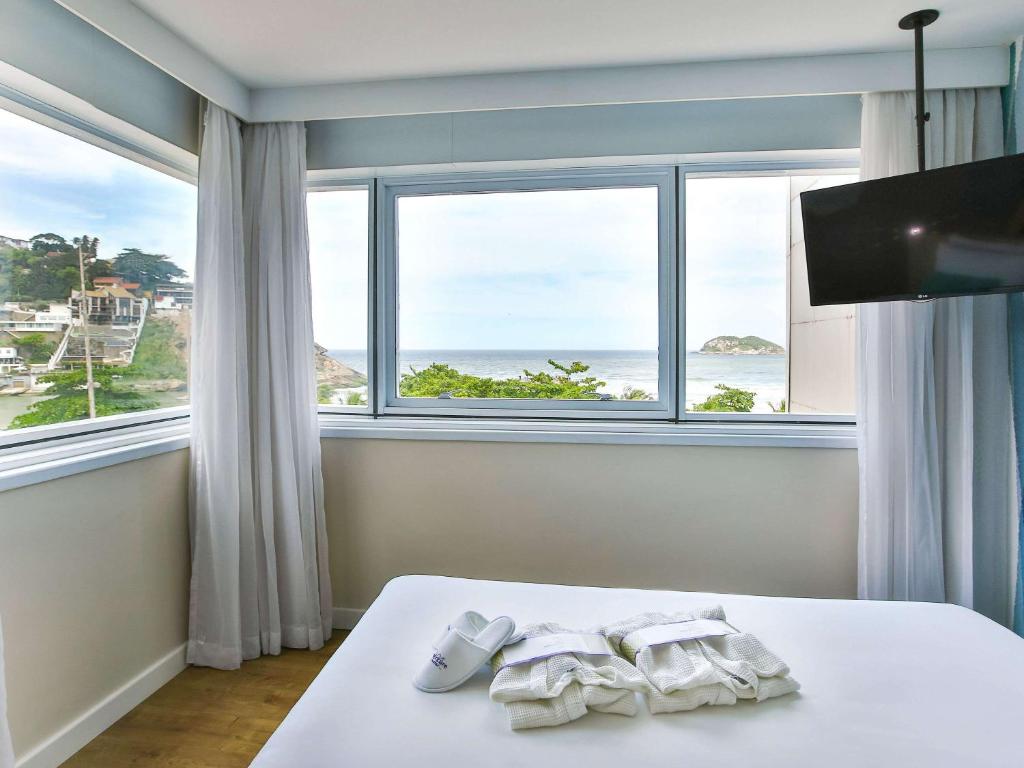 a bedroom with a bed with a view of the ocean at Mercure Rio de Janeiro Barra da Tijuca in Rio de Janeiro