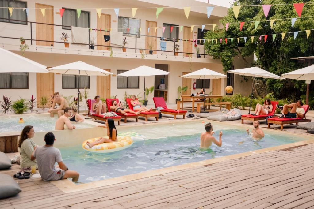 a group of people sitting in a swimming pool at Che Valladolid Hostel & Bar Adults Only in Valladolid