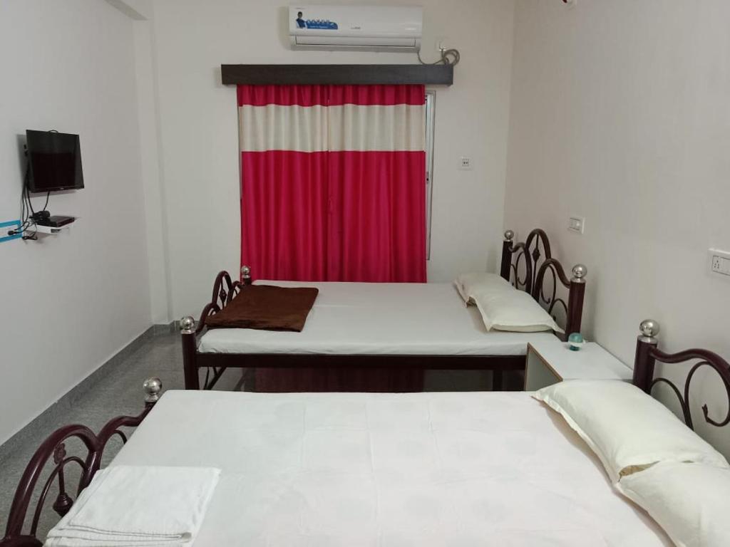 two beds in a room with a red curtain at Banpalashi Inn in Jhārgrām