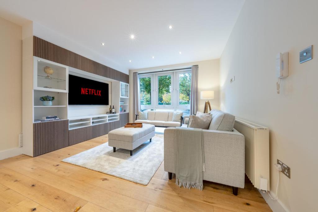 ein Wohnzimmer mit einem Sofa und einem TV in der Unterkunft Candler Mews - Twickenham in Twickenham
