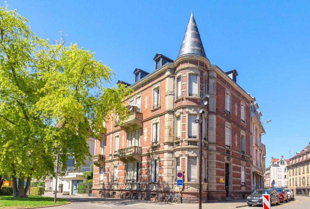 an old brick building with a pointed turret on a street at Appartement Luxueux Centre Ville in Colmar