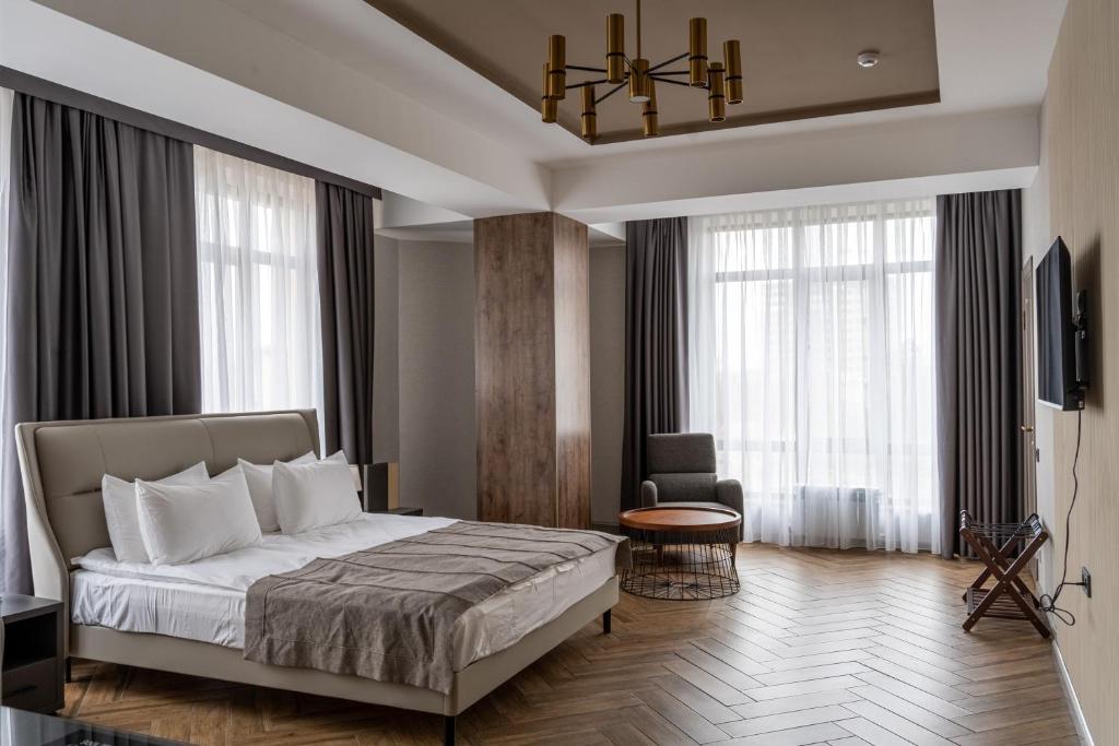 Habitación de hotel con cama, silla y ventanas en Five Hotel, en Bishkek