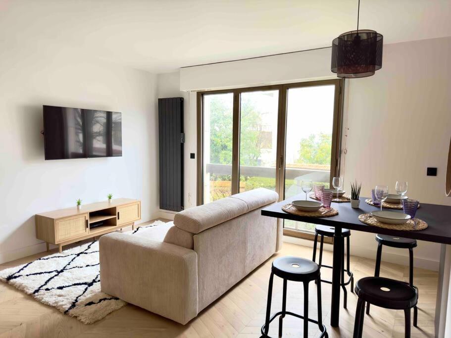 a living room with a couch and a table at Charmant Appartement Neuilly - 10mn Champs-Elysées in Neuilly-sur-Seine
