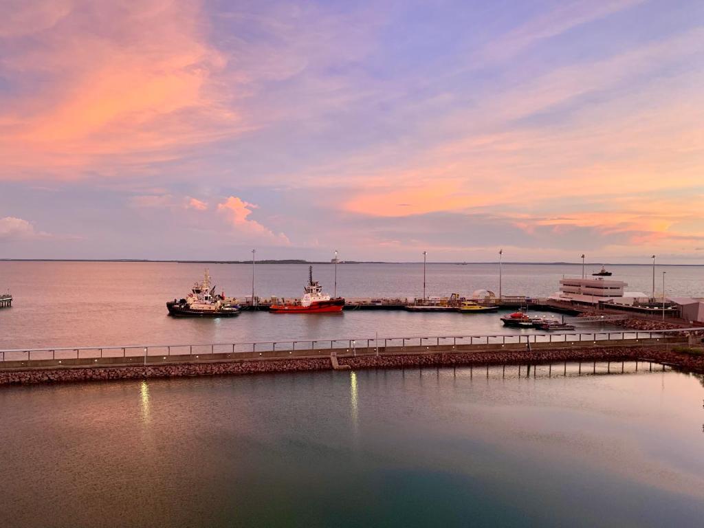 a dock with boats in the water at sunset at Serenity Peary - Executive 1brm at Darwin Waterfront with Sea Views in Darwin