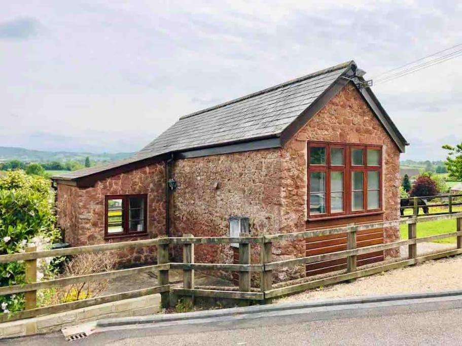 a brick cottage with a fence around it at Peaceful Open-Plan Cottage With A View in Wellington