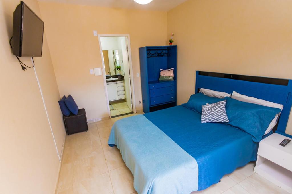 um quarto com uma cama azul e uma televisão em Otimo flat a 750m do mar Sta Monica Guarapari ES em Guarapari